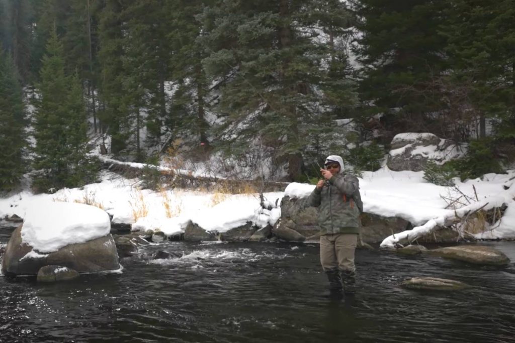 Angler fly fishing in cold weather while wearing layered clothing